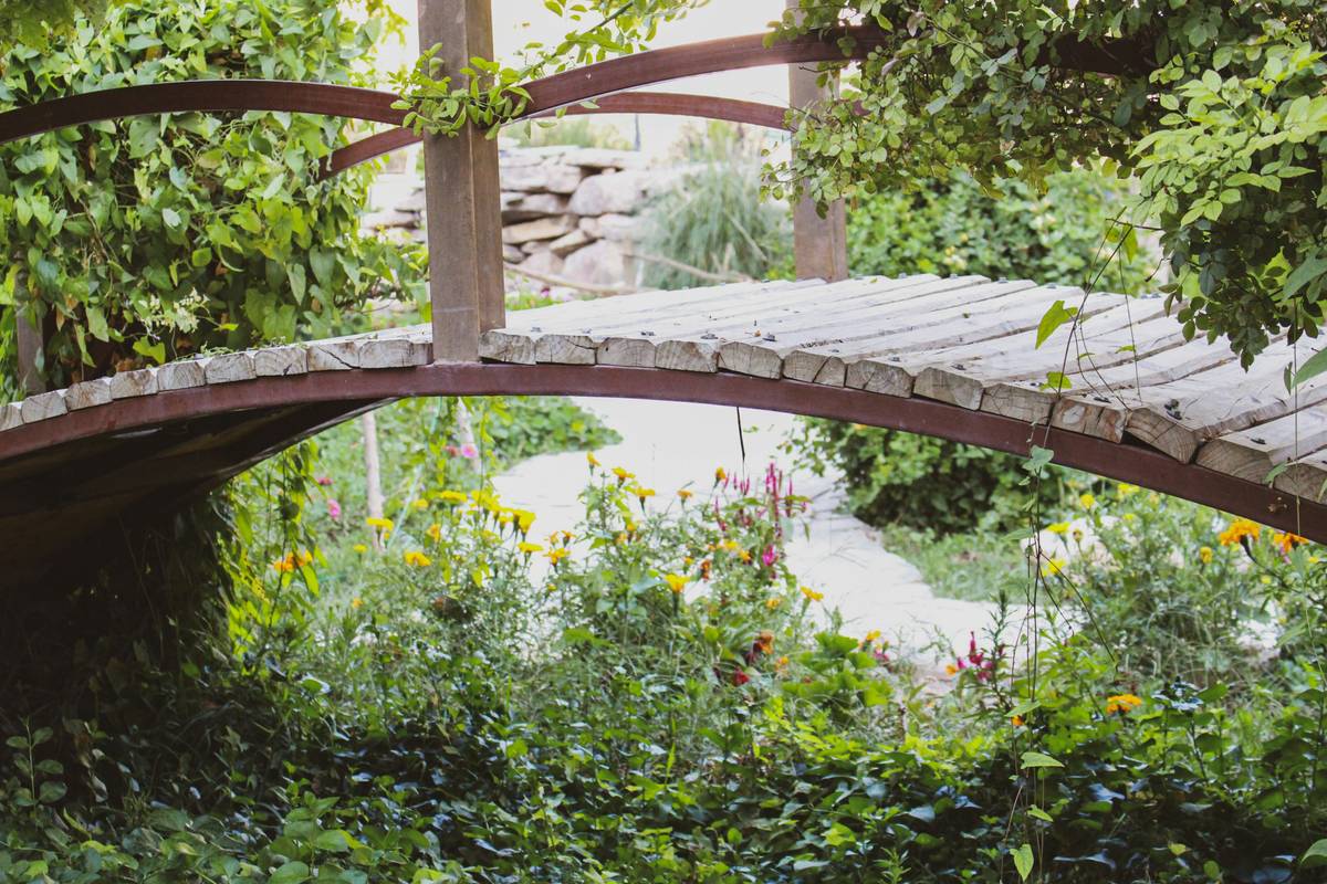 how to build garden bridge over small backyard pond with wooden planks and stone supports