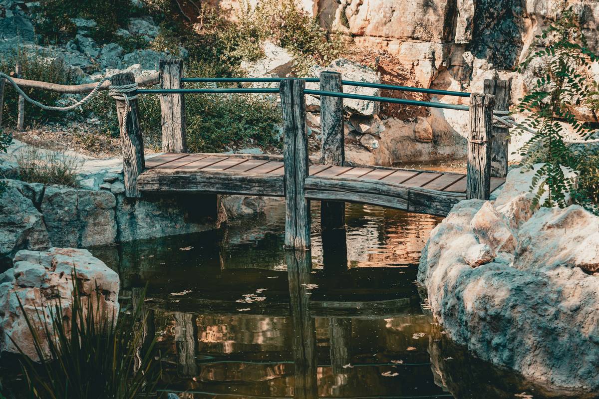simple diy garden bridge over a dry creek bed with wooden planks and stone borders